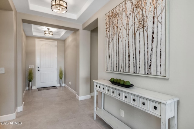 entryway featuring a raised ceiling and an inviting chandelier