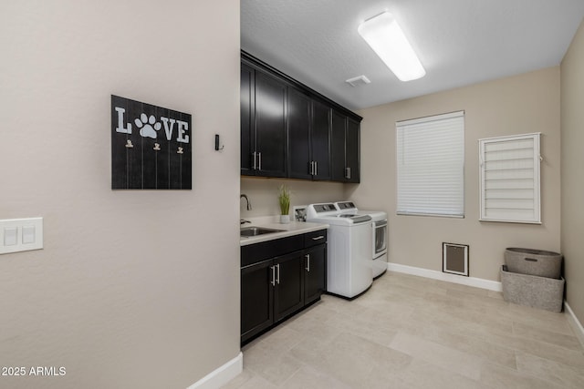 washroom with a textured ceiling, cabinets, washing machine and clothes dryer, and sink