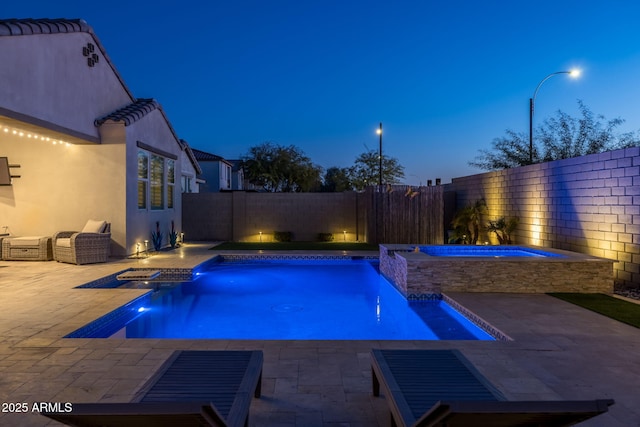 pool at dusk with pool water feature, a patio area, and an in ground hot tub