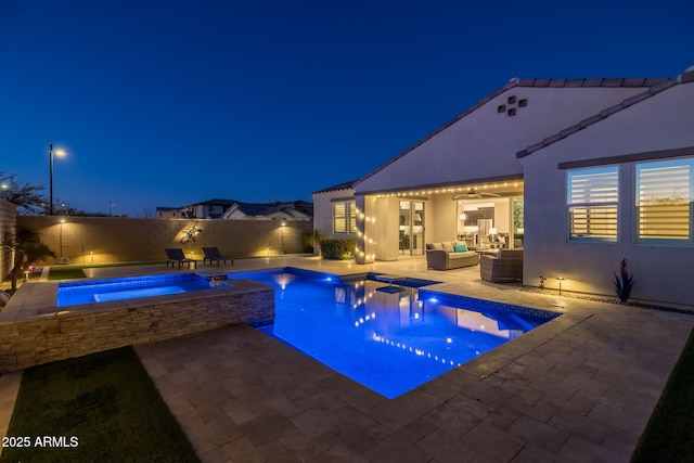 pool at night featuring an outdoor hangout area, an in ground hot tub, and a patio area