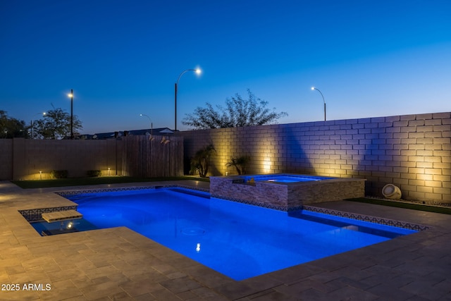 pool at dusk with an in ground hot tub