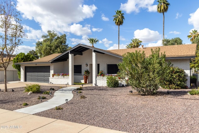 mid-century inspired home with concrete driveway, brick siding, an attached garage, and a shingled roof