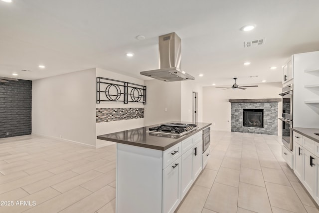 kitchen with visible vents, dark countertops, appliances with stainless steel finishes, open floor plan, and range hood