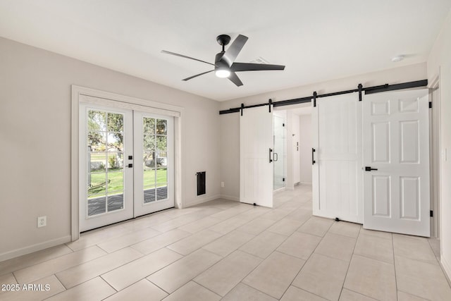 unfurnished room with a ceiling fan, light tile patterned flooring, baseboards, and a barn door