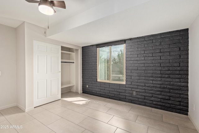 unfurnished bedroom featuring light tile patterned floors, brick wall, and baseboards