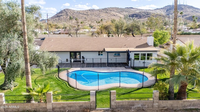 view of swimming pool with a yard, a fenced in pool, a mountain view, and fence