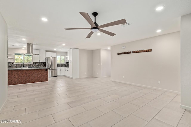 unfurnished living room featuring ceiling fan, recessed lighting, a sink, visible vents, and baseboards