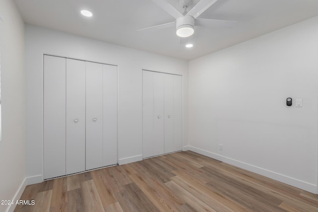 unfurnished bedroom featuring light wood-type flooring, two closets, and ceiling fan