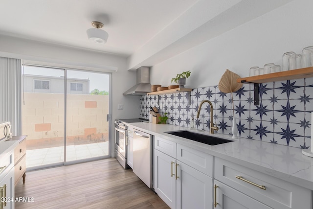 kitchen with sink, wall chimney exhaust hood, decorative backsplash, appliances with stainless steel finishes, and white cabinetry