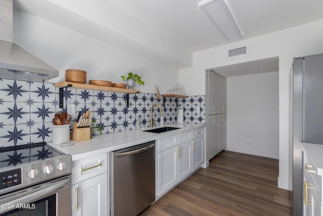 kitchen featuring sink, stainless steel appliances, wall chimney range hood, tasteful backsplash, and white cabinets