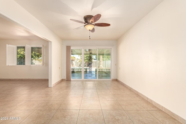 tiled empty room with ceiling fan and plenty of natural light