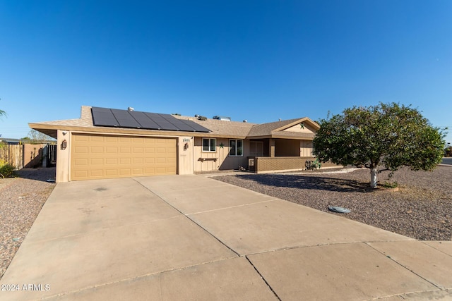 ranch-style house with a garage and solar panels