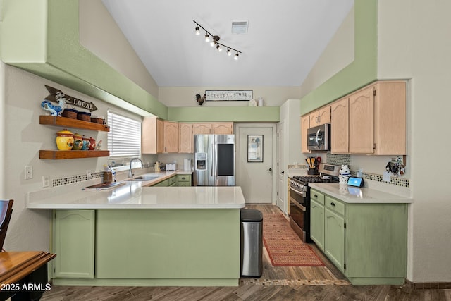 kitchen with light brown cabinetry, vaulted ceiling, kitchen peninsula, and appliances with stainless steel finishes