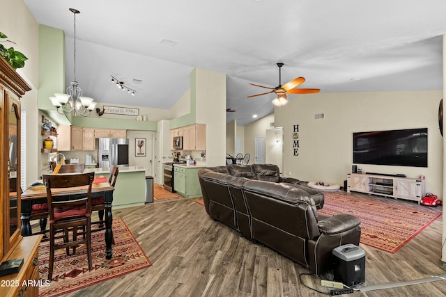 living room featuring lofted ceiling, ceiling fan with notable chandelier, and wood-type flooring