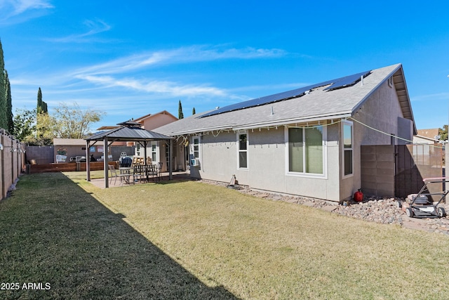 back of property featuring a gazebo, a yard, and solar panels