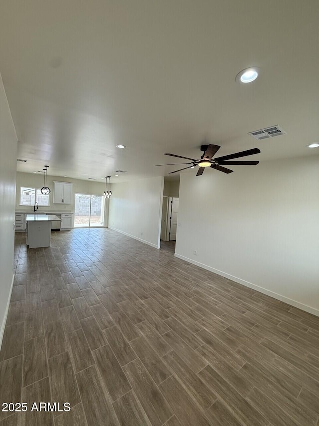 unfurnished living room with dark wood-type flooring, ceiling fan, and sink