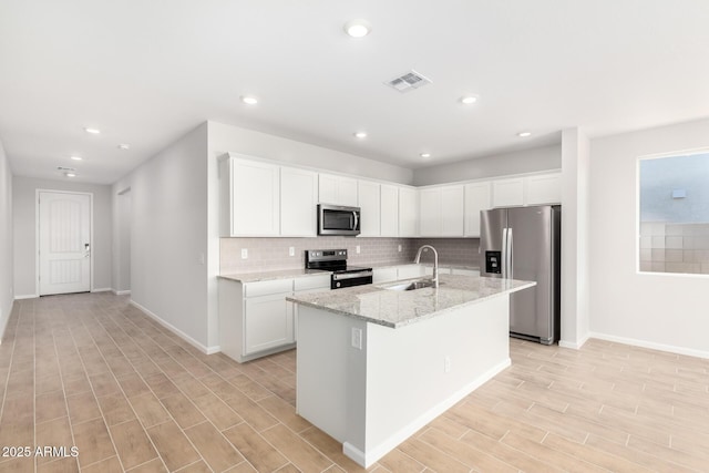 kitchen with sink, stainless steel appliances, white cabinetry, and an island with sink