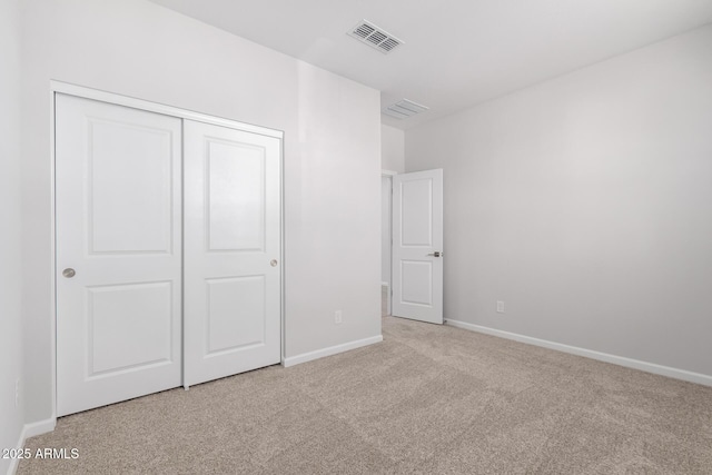 unfurnished bedroom featuring light carpet and a closet