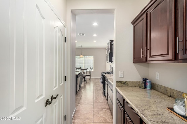 5016 S Curie Way, Mesa, AZ 85212 - kitchen with gas range oven, recessed lighting, light tile patterned floors, dark brown cabinets, and light stone counters