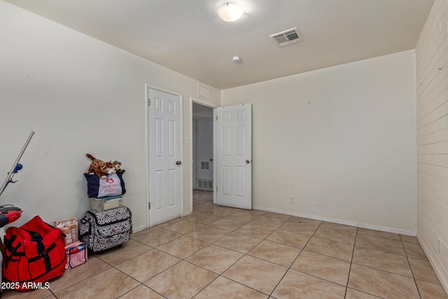 tiled spare room featuring brick wall