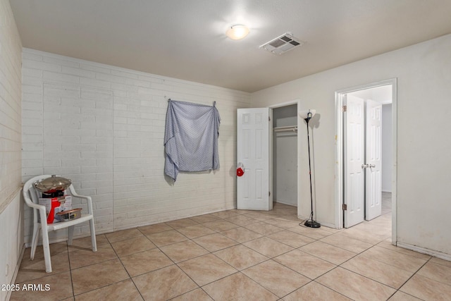 tiled spare room featuring brick wall