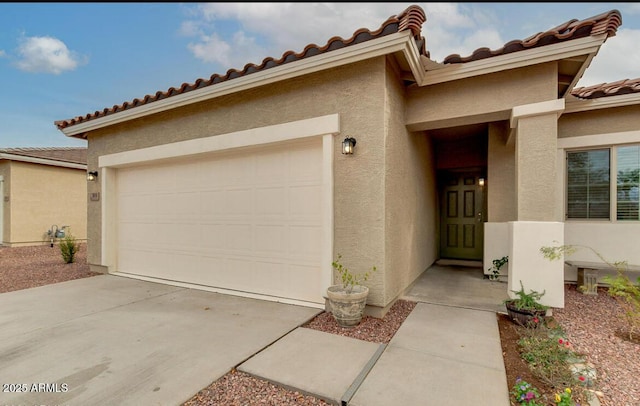 view of front of property with stucco siding, an attached garage, a tile roof, and driveway