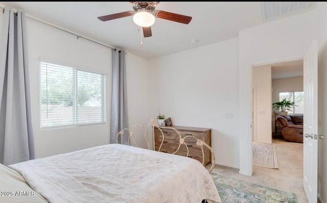 bedroom with light colored carpet, visible vents, and ceiling fan