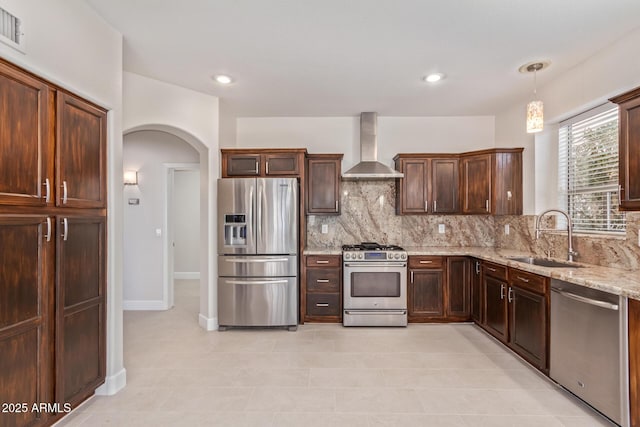 kitchen featuring sink, backsplash, hanging light fixtures, stainless steel appliances, and wall chimney exhaust hood