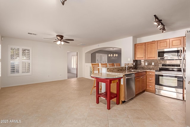 kitchen with sink, light tile patterned floors, appliances with stainless steel finishes, and decorative backsplash