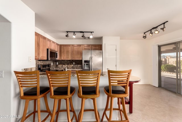 kitchen featuring decorative backsplash, a breakfast bar, appliances with stainless steel finishes, and kitchen peninsula