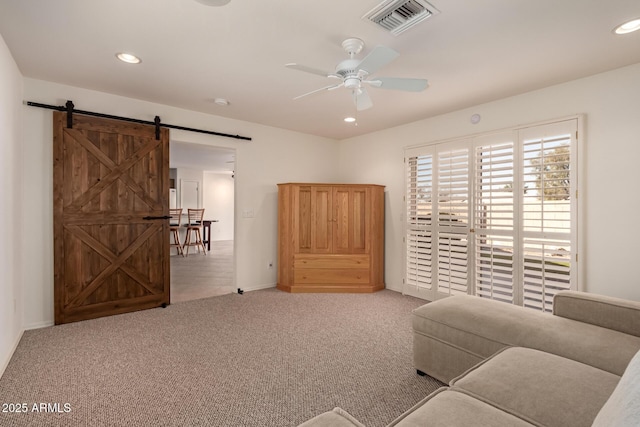 living room with ceiling fan, a barn door, and carpet floors