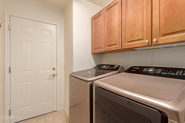 clothes washing area with light tile patterned flooring, cabinets, and washer and dryer