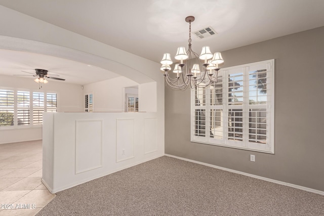 carpeted spare room featuring ceiling fan with notable chandelier