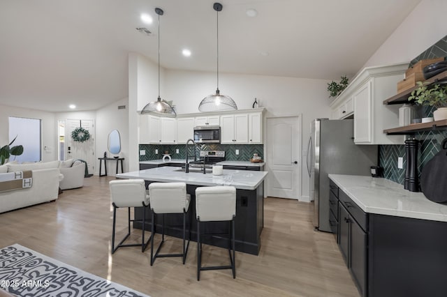 kitchen featuring open shelves, a kitchen bar, appliances with stainless steel finishes, and white cabinets