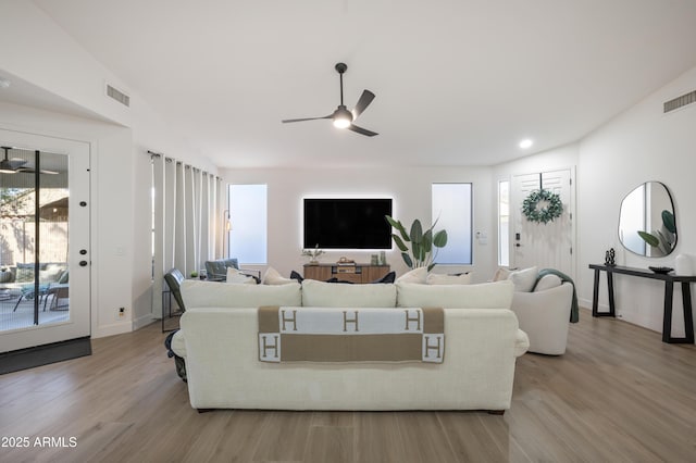 living room featuring visible vents, lofted ceiling, ceiling fan, and wood finished floors