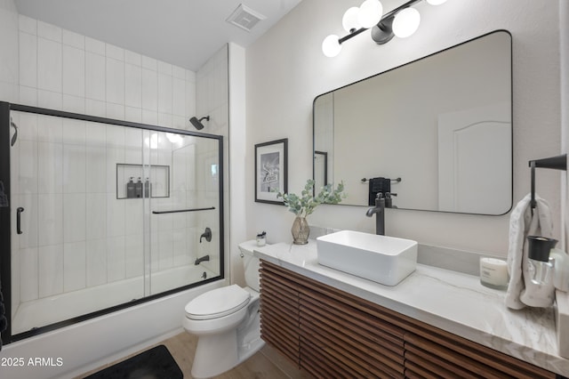 full bathroom featuring visible vents, toilet, wood finished floors, enclosed tub / shower combo, and vanity