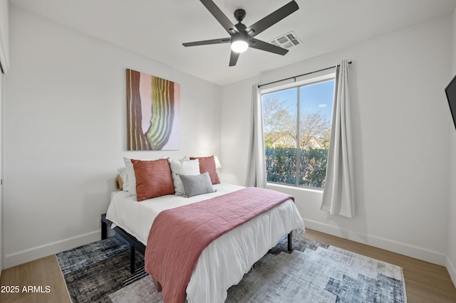 bedroom featuring visible vents, baseboards, and wood finished floors