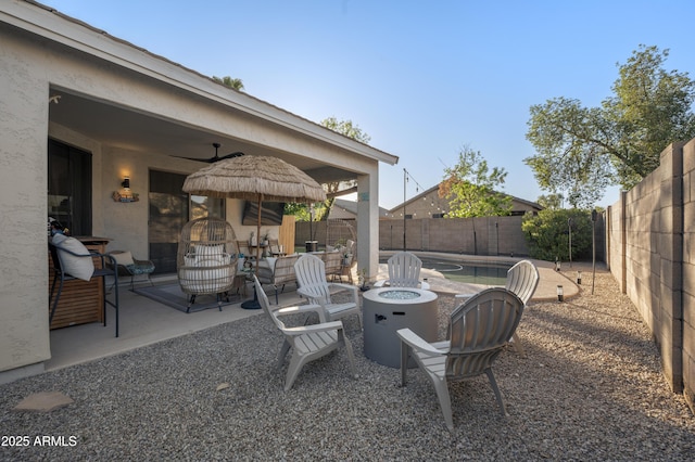 view of patio featuring a ceiling fan, a fire pit, and a fenced backyard