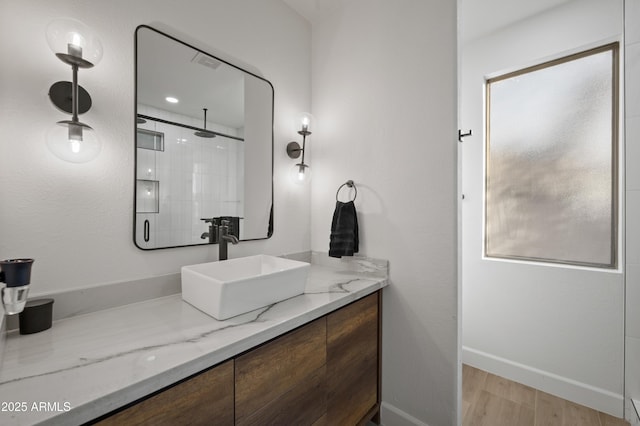 full bath with vanity, a shower, baseboards, and wood finished floors