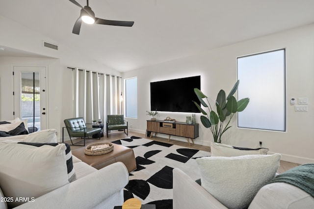 living room featuring visible vents, ceiling fan, baseboards, and lofted ceiling