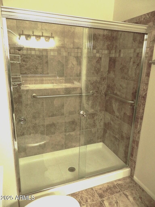 full bathroom featuring baseboards, toilet, and a stall shower