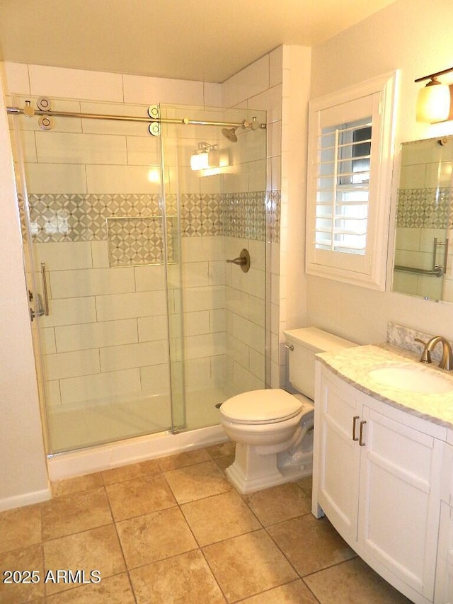 bathroom featuring toilet, vanity, tile patterned floors, and a stall shower