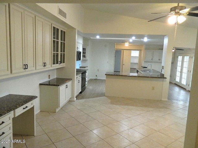 kitchen featuring a ceiling fan, a sink, dark stone countertops, and black appliances