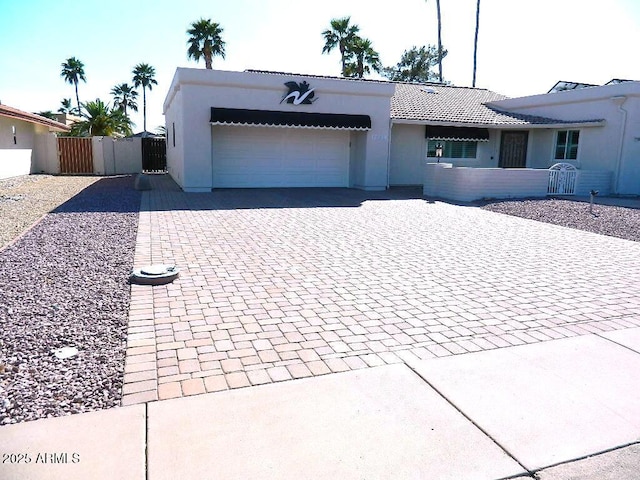ranch-style house featuring a gate, decorative driveway, a tiled roof, a garage, and stucco siding