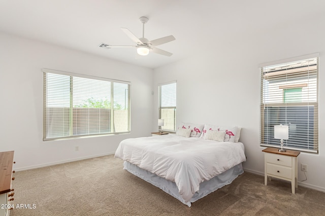 carpeted bedroom with multiple windows and ceiling fan