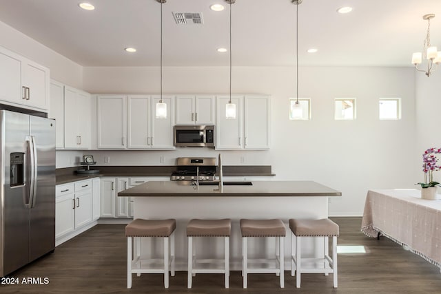 kitchen with a center island with sink, white cabinets, decorative light fixtures, and stainless steel appliances