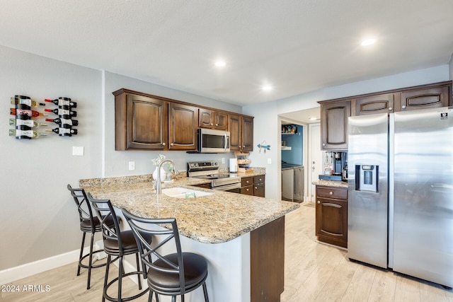 kitchen featuring kitchen peninsula, a breakfast bar, sink, and appliances with stainless steel finishes