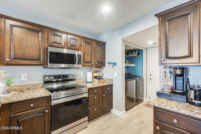 kitchen featuring independent washer and dryer, light wood-type flooring, stainless steel appliances, and dark brown cabinetry