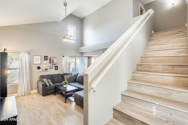 stairway featuring wood-type flooring, high vaulted ceiling, and ceiling fan