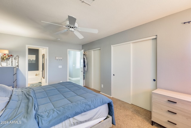 bedroom featuring ceiling fan, light carpet, connected bathroom, and two closets